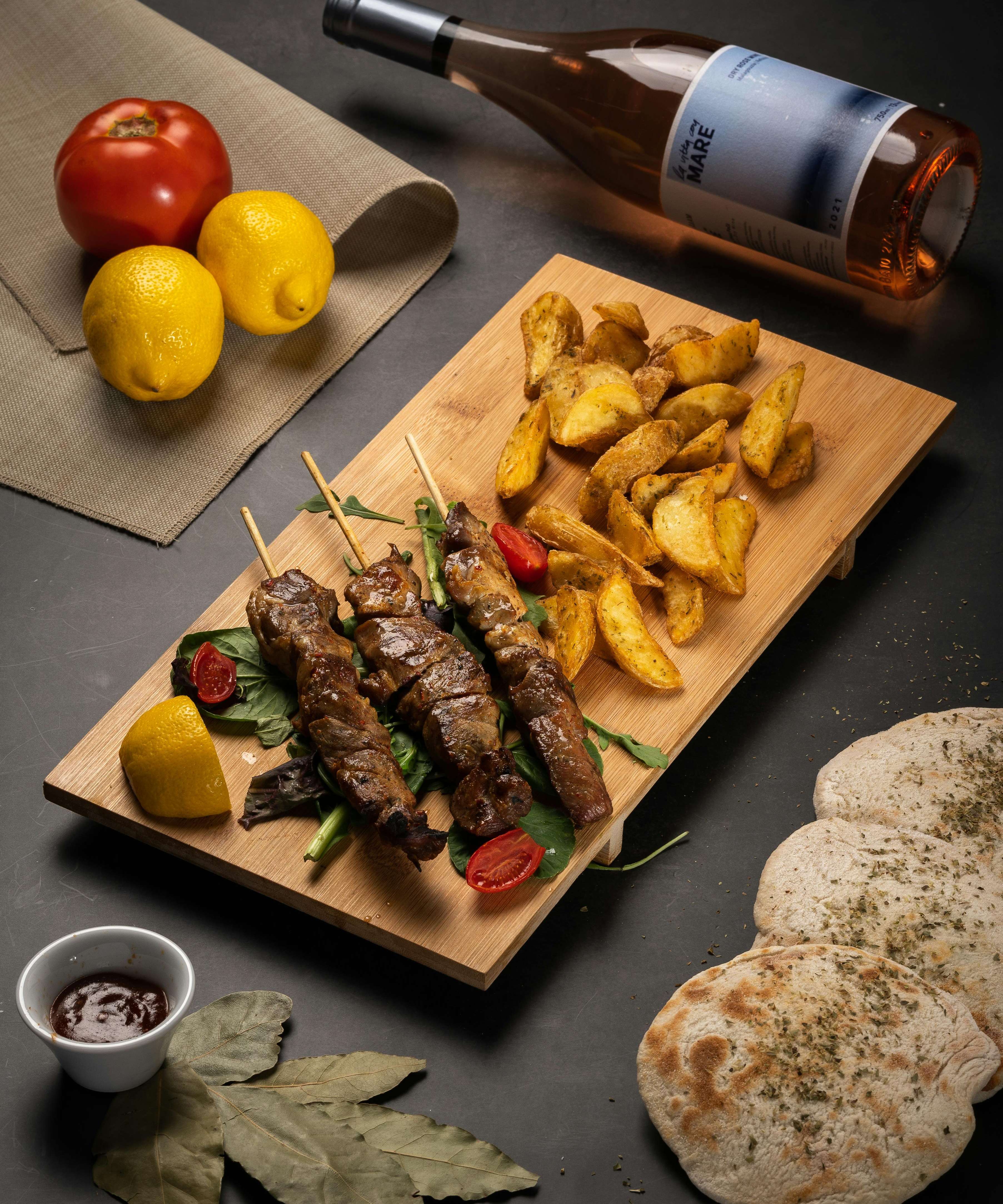 Delicious Greek souvlaki skewers with roasted potatoes and wine. Perfect for an authentic Greek dining experience.